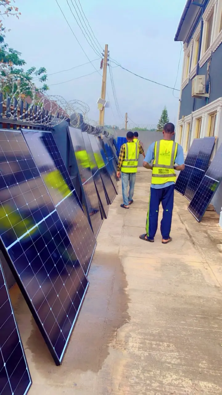 Solar panels staged in a row along the compound wall before being carried up.
