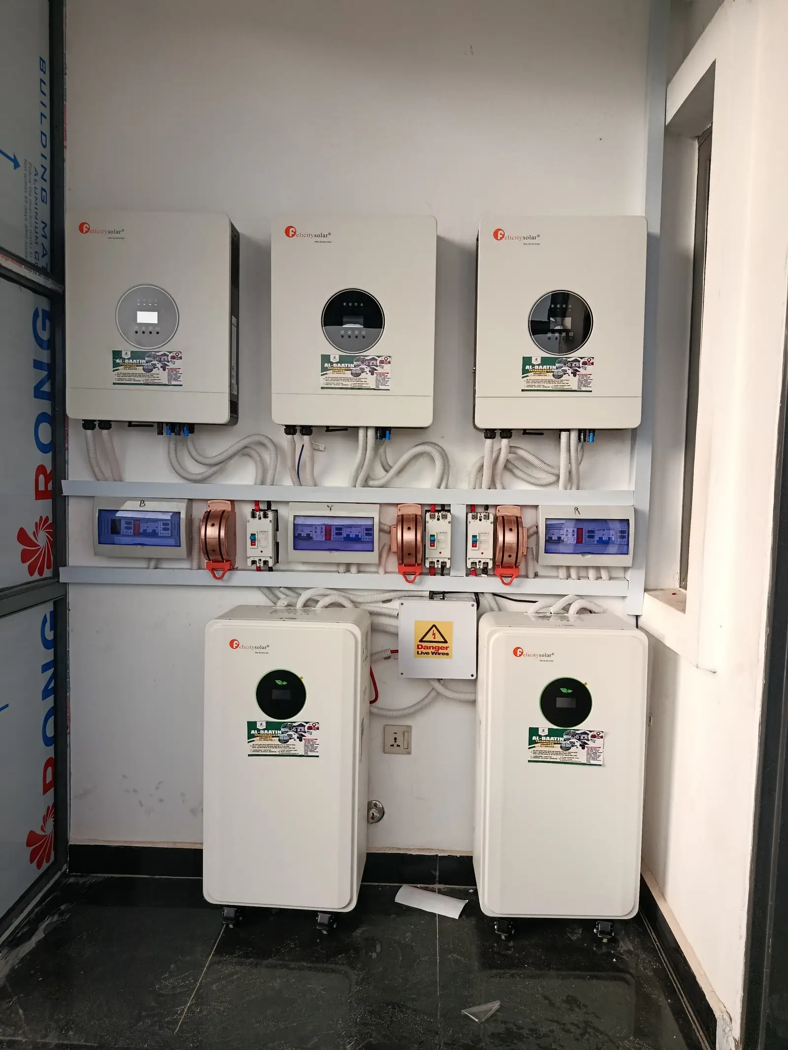 The same inverter wall straight on, showing the breaker panel and cable runs between the units.