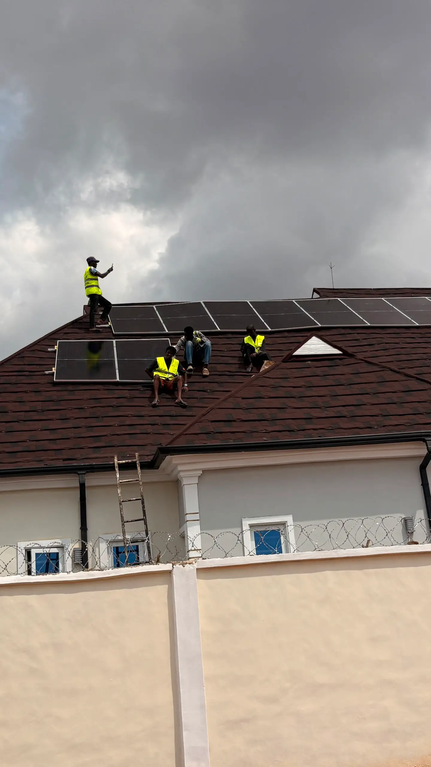 Fitters in hi-vis vests mounting solar panels on a pitched roof.