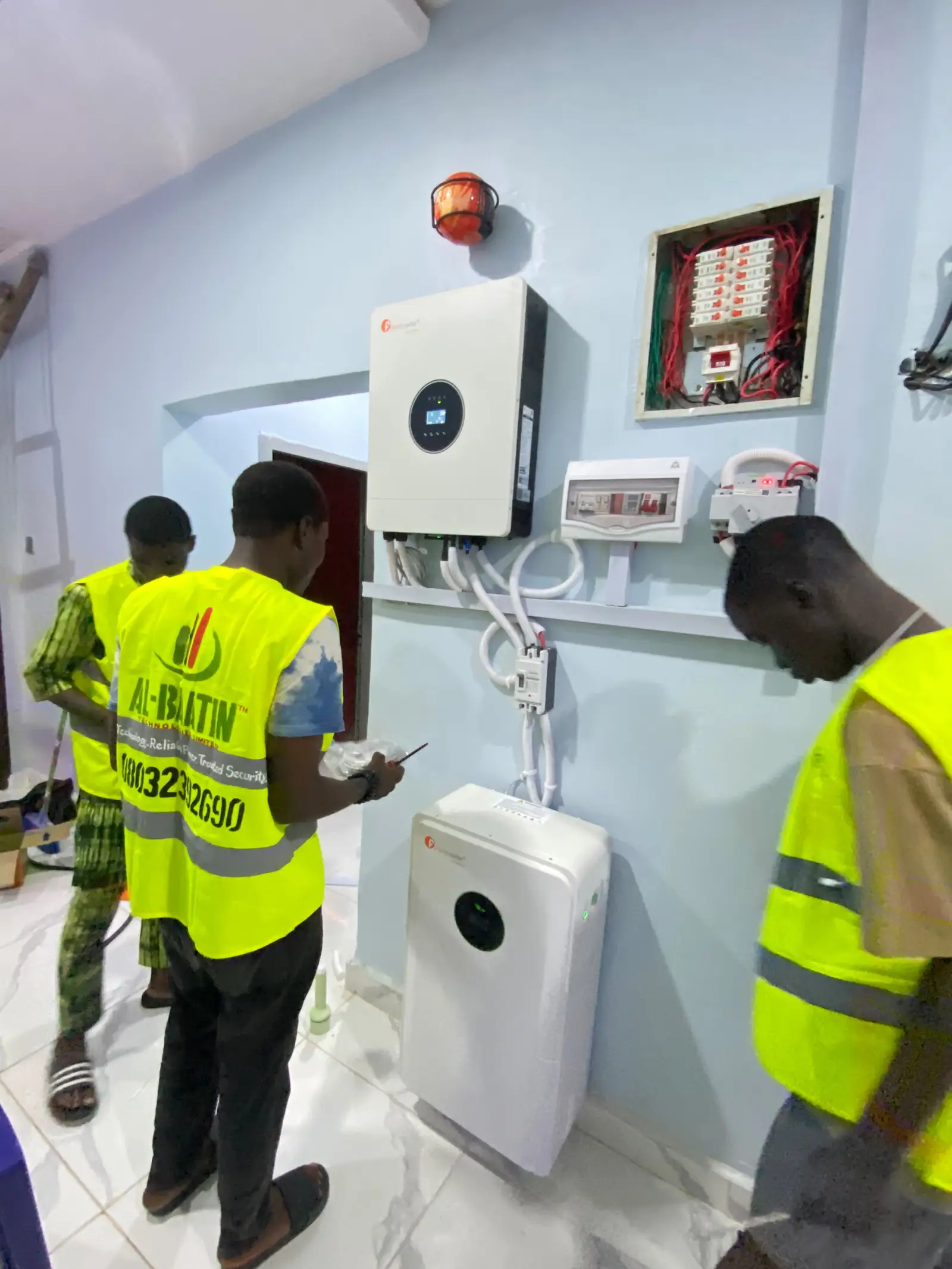 Al-Baatin fitters beside the completed inverter and battery installation.