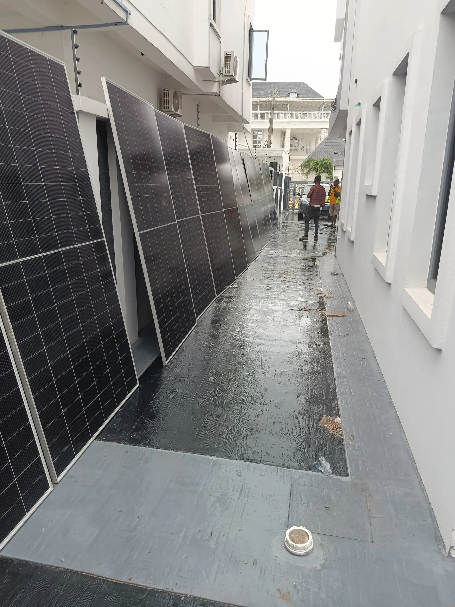 Solar panels staged along the side passage of the house, ready to be carried up.