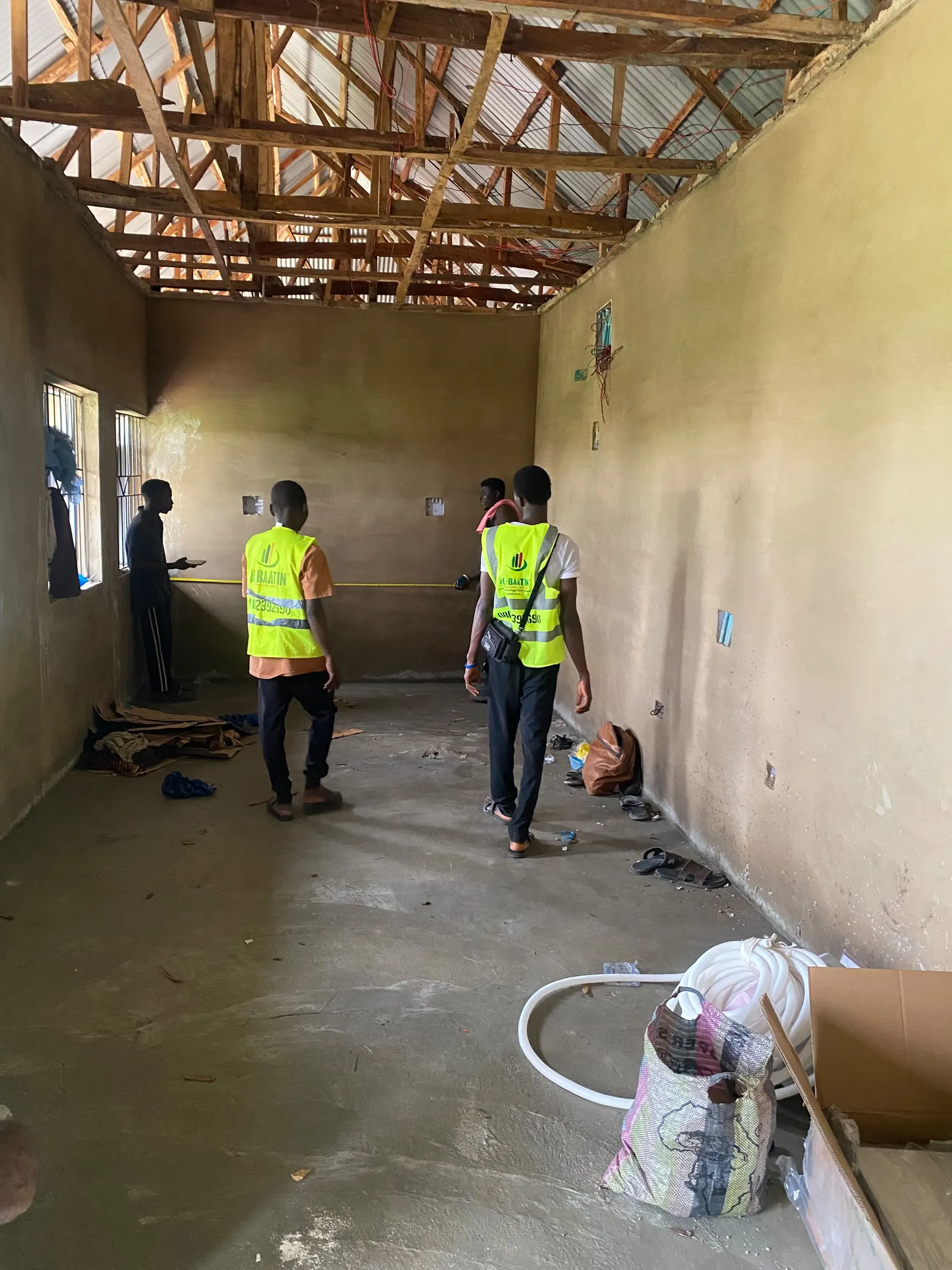 Two of the crew measuring up inside the empty farm building before the wiring goes in.