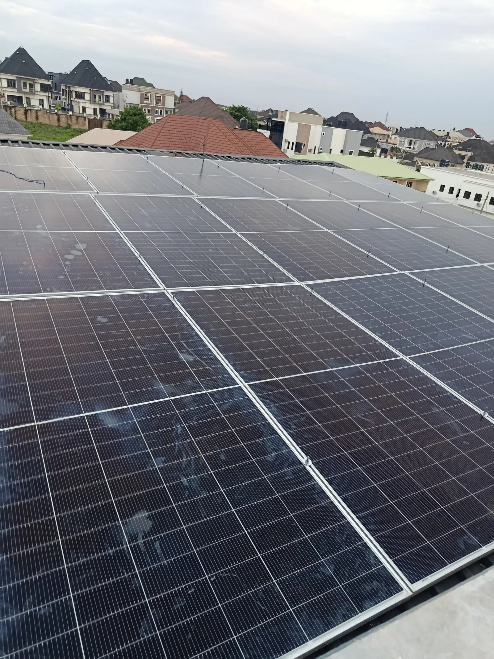 The finished solar array seen along the roofline at dusk, panels angled across the full width of the roof.