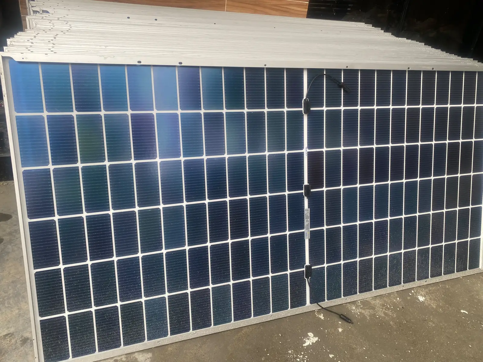 A close-up of a 650W solar panel resting on its edge before installation.