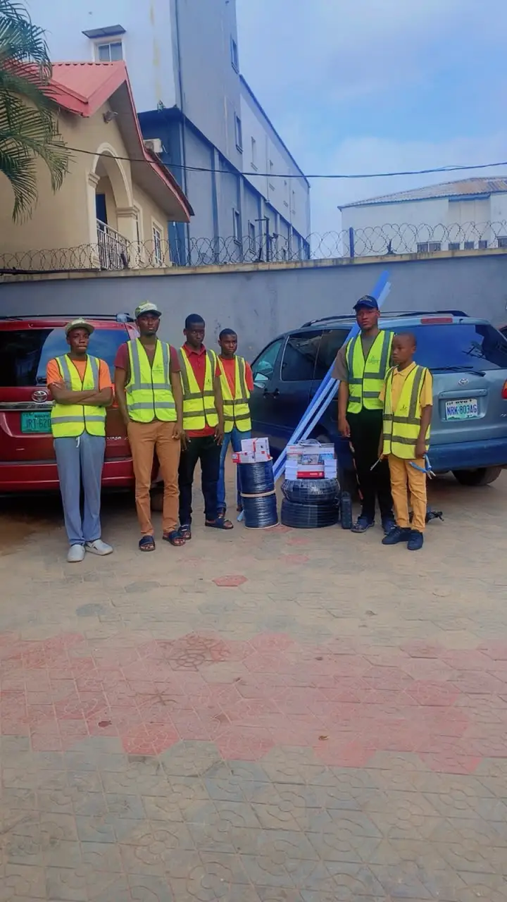 The Al-Baatin crew in branded hi-vis vests standing with coils of cable and boxed equipment in front of their vans before a job.